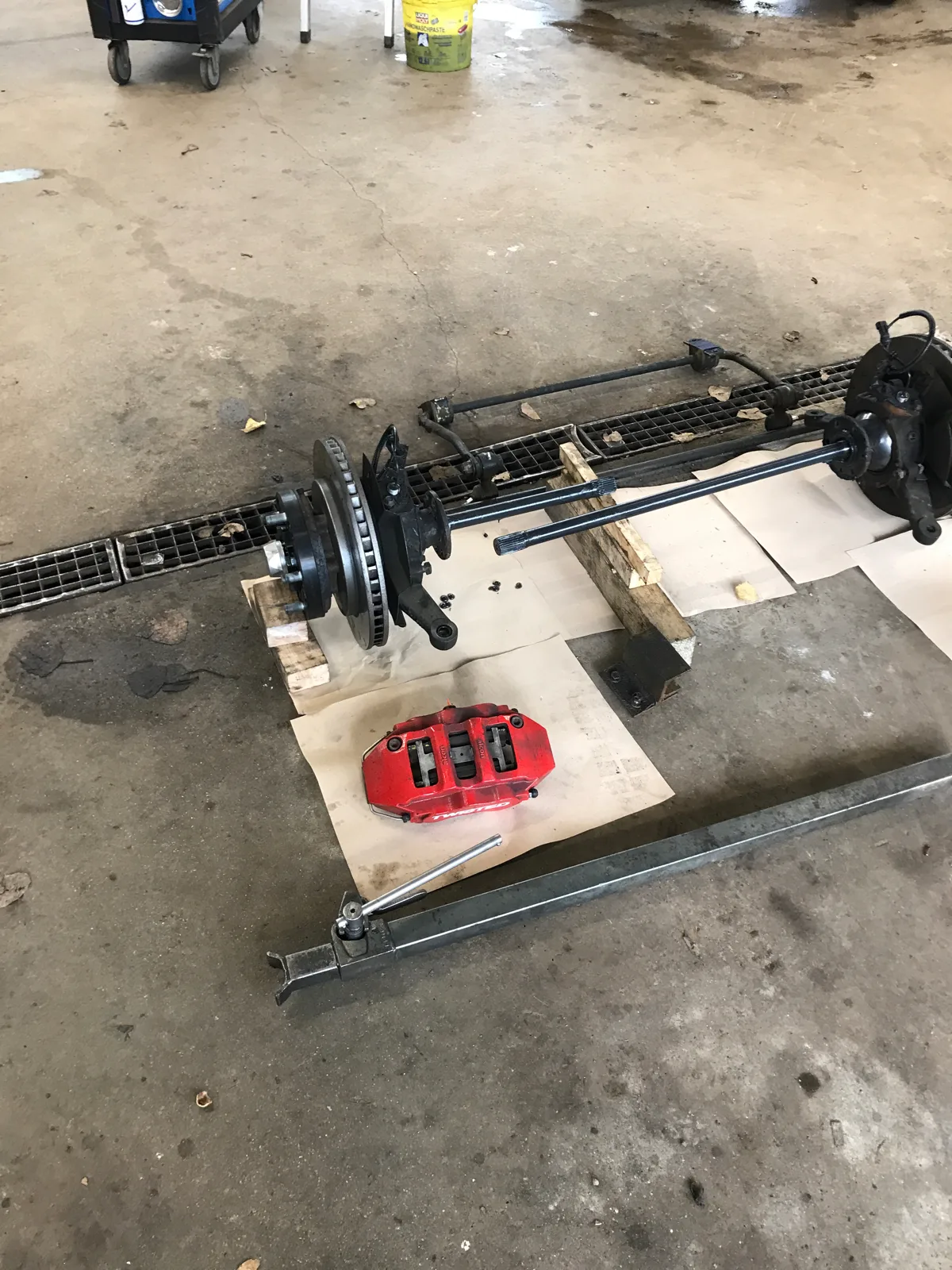 Zerlegte Vorderachse mit Bremsscheiben, Steckachsen und rotem Bremssattel